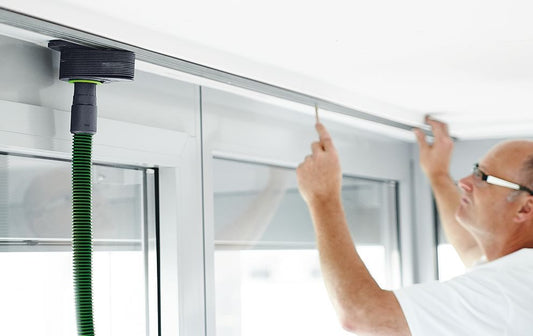 Festool Vakuum-Spanndüse CT-W mit grünem Saugschlauch an Deckenleiste montiert, Handwerker befestigt Werkstück