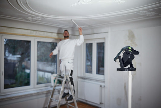 Festool Stativ ST DUO 200 auf Deckenleuchte positioniert, Arbeiter auf Leiter beim Deckenverputz