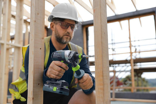 Festool Akku-Bohrschrauber TBX 4 mit BP 18 Akkupack im Einsatz auf Baustelle, Handwerker mit Schutzausrüstung.