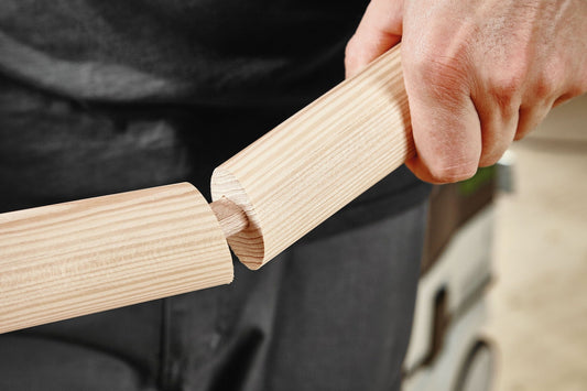 Festool DOMINO Dübel Buche wird in Holz eingesteckt, zeigt Leimtaschen und Längsrillen für sichere Verbindung