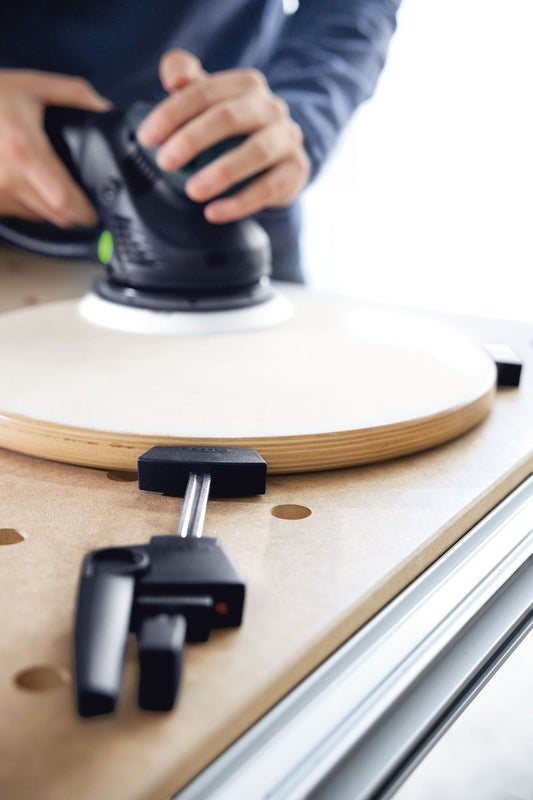 Festool MFT/3 Multifunktionstisch mit Exzenterschleifer beim Schleifen einer Sperrholzplatte mit Lochrastung