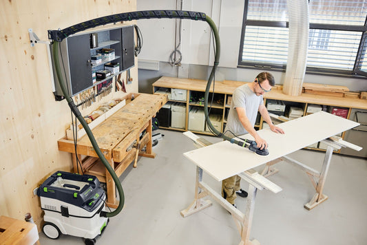 Festool Absaugarm CT-ASA FLX W bei Anwendung zum Schleifen weißer Platte in Werkstatt mit Absauganlage