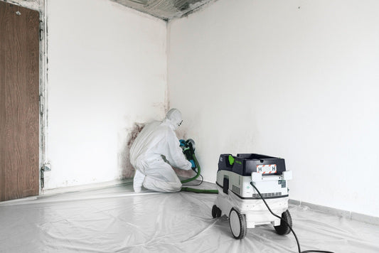 Festool CLEANTEC CTH 26 EI Absaugmobil im Einsatz bei Sanierungsarbeiten mit Schutzanzug und Schleifer