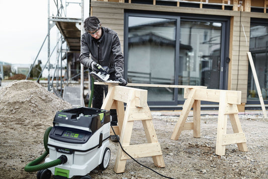 Festool CLEANTEC CTL 26 EI AC Absaugmobil im Einsatz beim Schleifen eines Holzbretts auf Baustelle mit Absaugschlauch