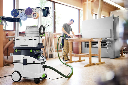 Festool CTL 36 EI Absaugmobil in Werkstatt mit Zubehörhalter und Schlauch, im Einsatz neben Handwerker